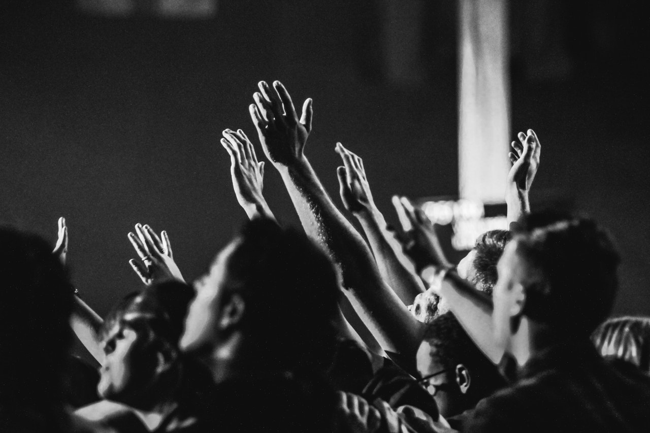 Raised hands and people in a ministry setting, demonstrating community engagement.