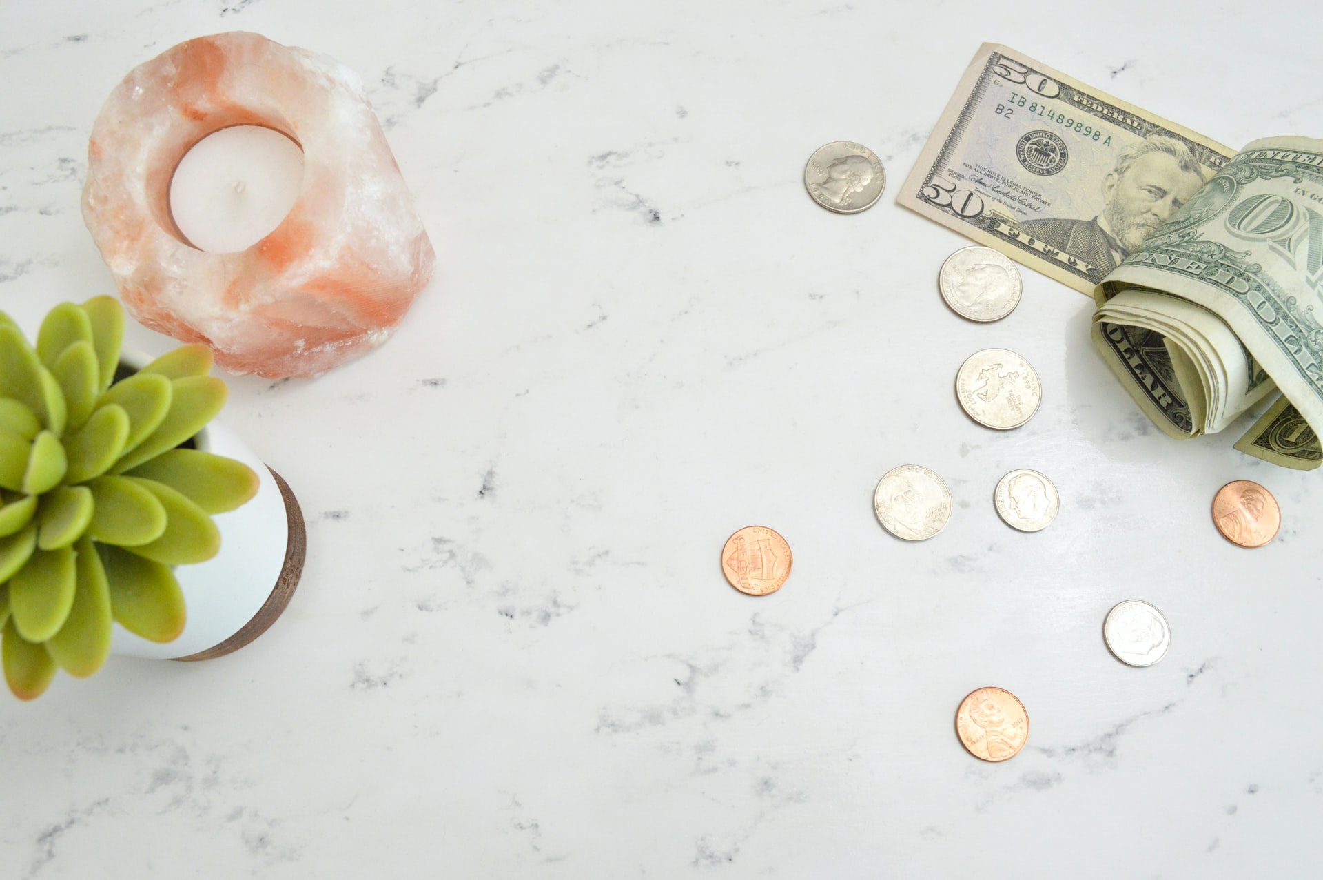 Salt lamp, coins, and a fifty dollar bill representing financial tips for young adults.